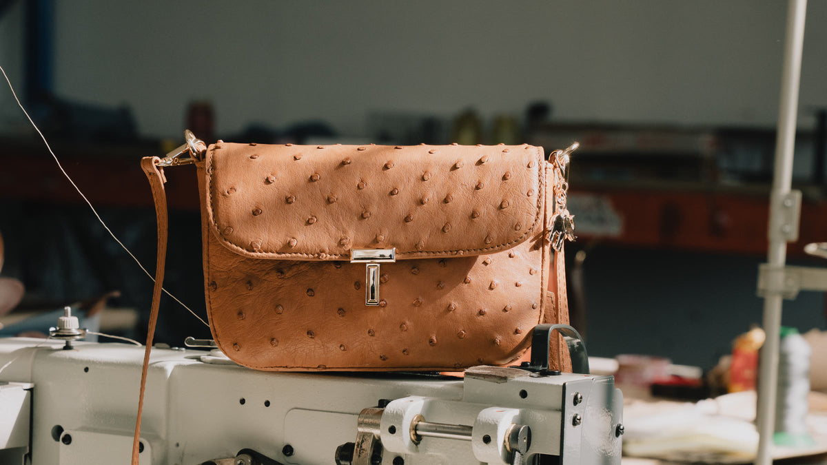 Tan ostrich crossbody bag resting on a sewing machine in the Woodstock workshop