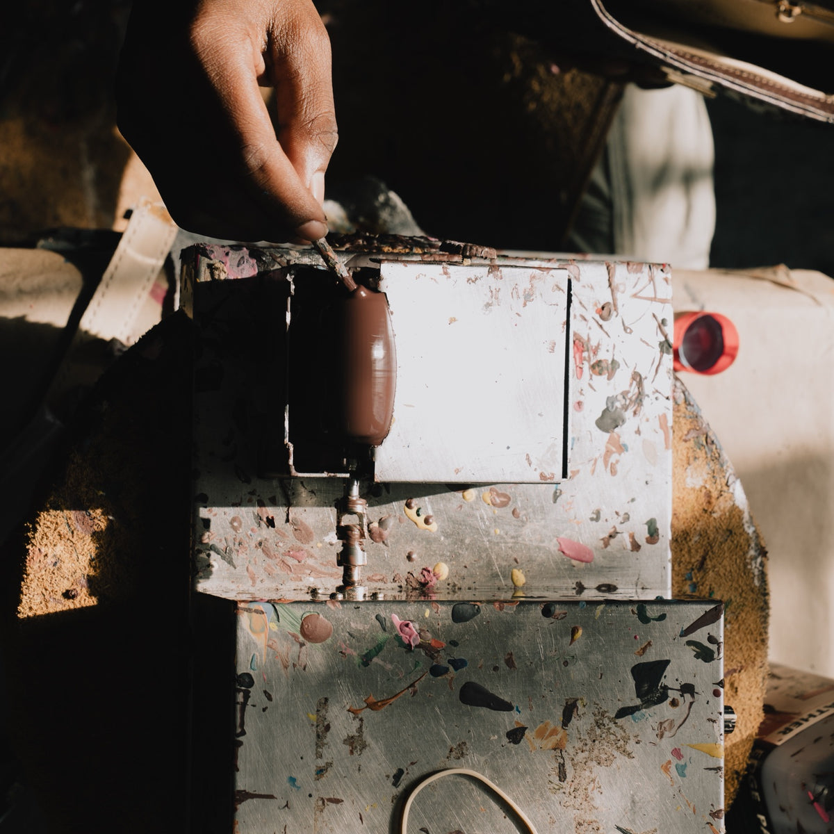 An artisan's hands edge-finishing a leather strap in the Tuska atelier