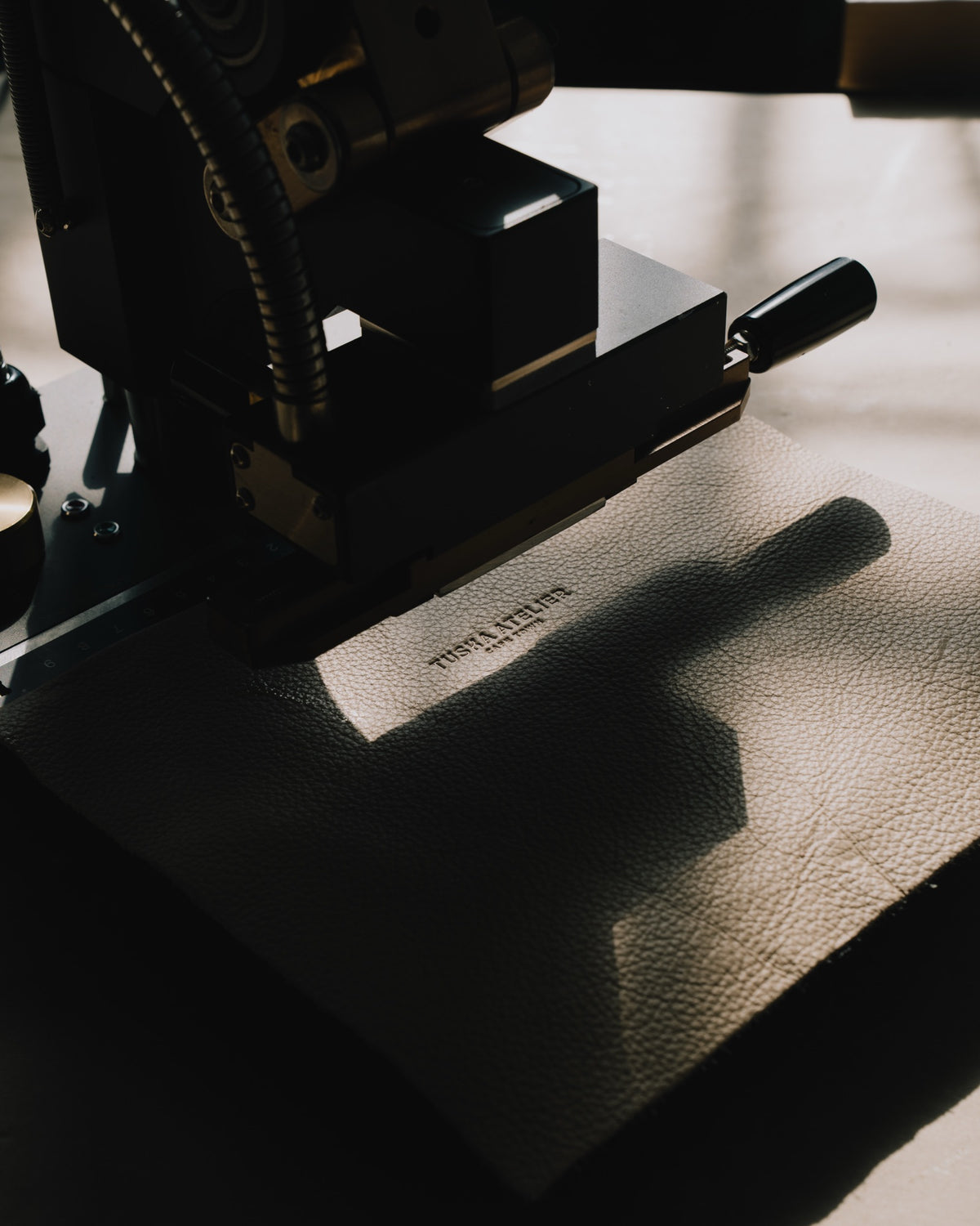 The Tuska Atelier mark being hot-stamped into full-grain leather